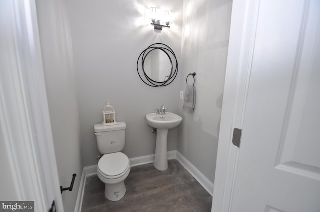 bathroom with toilet, a sink, baseboards, and wood finished floors