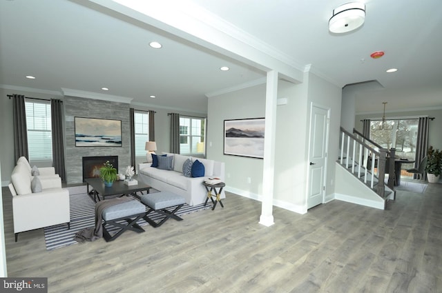 living room with crown molding, a tile fireplace, and light hardwood / wood-style flooring