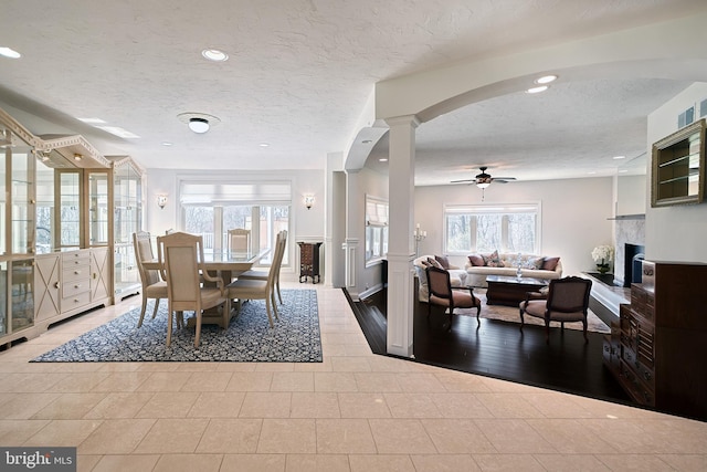 dining area with ornate columns, a textured ceiling, ceiling fan, and light tile flooring