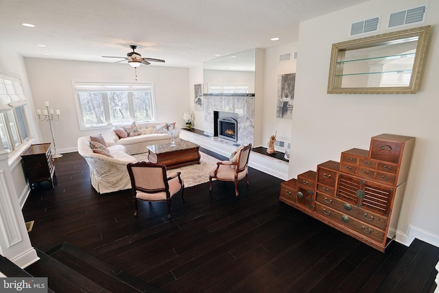 living room with a fireplace, ceiling fan, and dark wood-type flooring