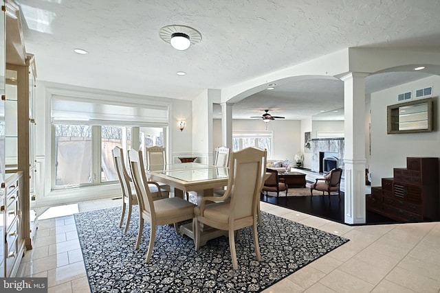 dining room featuring a textured ceiling, ceiling fan, decorative columns, and light tile flooring