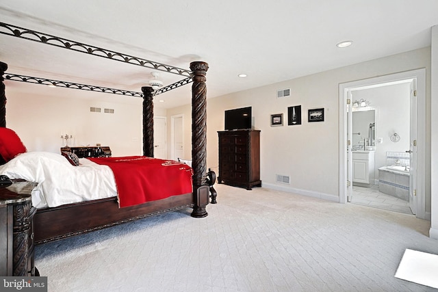 bedroom with ceiling fan, connected bathroom, and light carpet