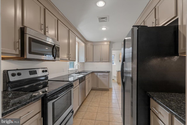 kitchen featuring sink, dark stone countertops, light tile floors, and stainless steel appliances