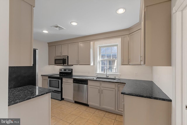 kitchen with dark stone countertops, stainless steel appliances, light tile floors, and sink