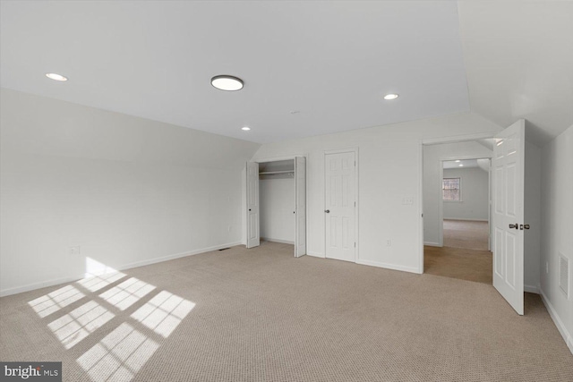 unfurnished bedroom with light colored carpet and lofted ceiling