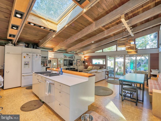 kitchen with white refrigerator with ice dispenser, white cabinetry, a wealth of natural light, and lofted ceiling with skylight