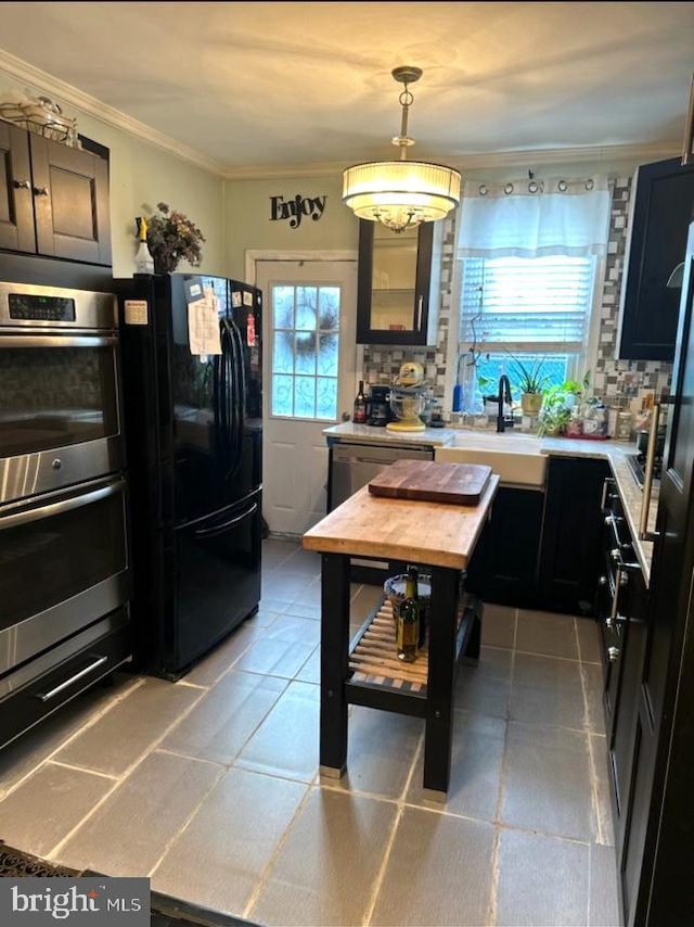 kitchen featuring light tile flooring, tasteful backsplash, black refrigerator, sink, and double oven