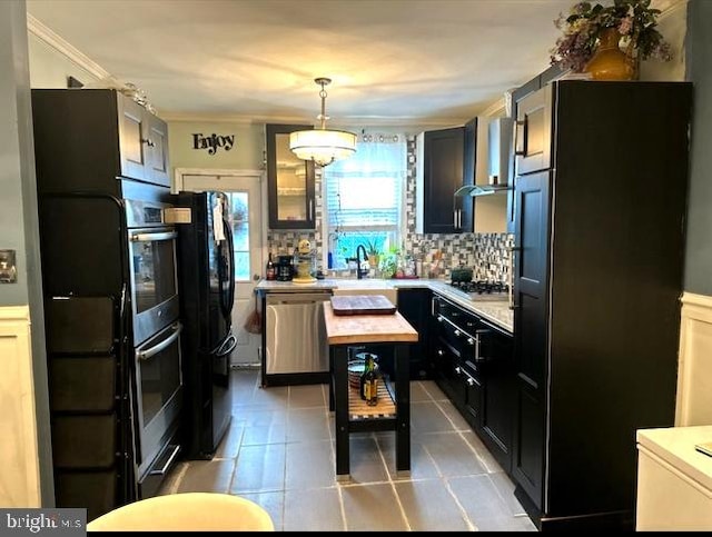 kitchen featuring tasteful backsplash, crown molding, stainless steel appliances, pendant lighting, and light tile flooring