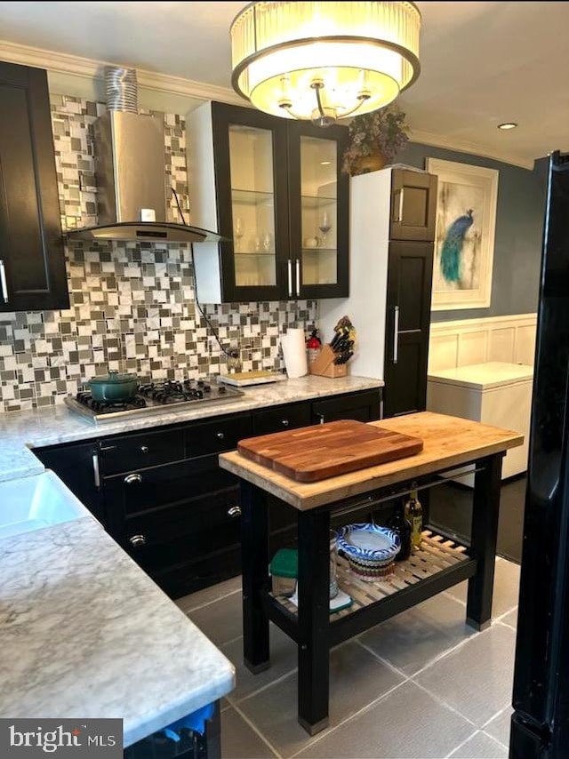 kitchen with crown molding, wall chimney exhaust hood, tasteful backsplash, and stainless steel gas cooktop