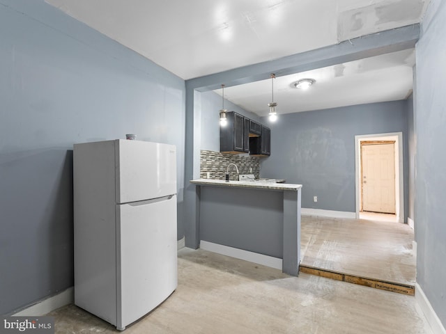 kitchen featuring light hardwood / wood-style floors, white fridge, tasteful backsplash, hanging light fixtures, and sink