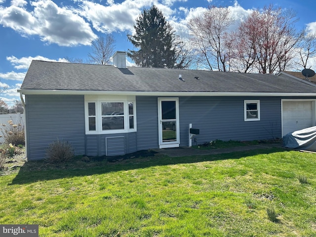 rear view of property featuring a yard and a garage