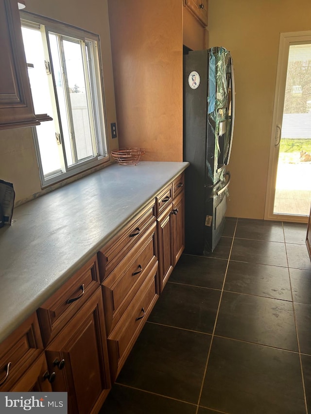 kitchen featuring dark tile patterned flooring and black refrigerator