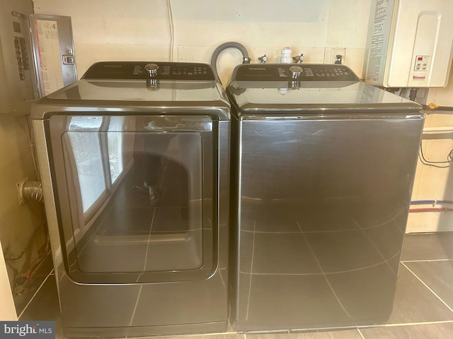 clothes washing area featuring washer and clothes dryer, light tile patterned floors, and tankless water heater