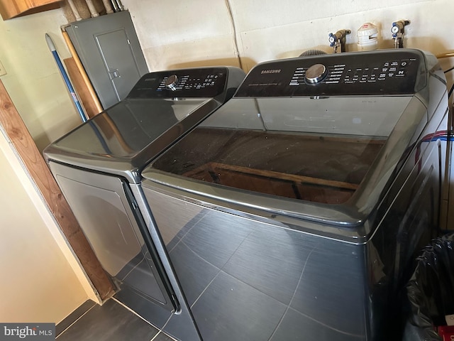 clothes washing area with washer and dryer and dark tile patterned flooring