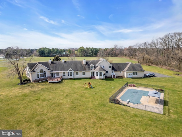 rear view of house with a yard and a covered pool