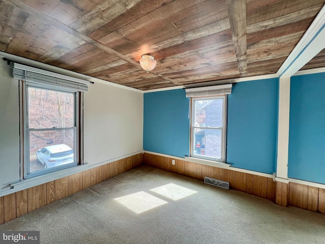 empty room featuring wooden walls, wooden ceiling, and carpet