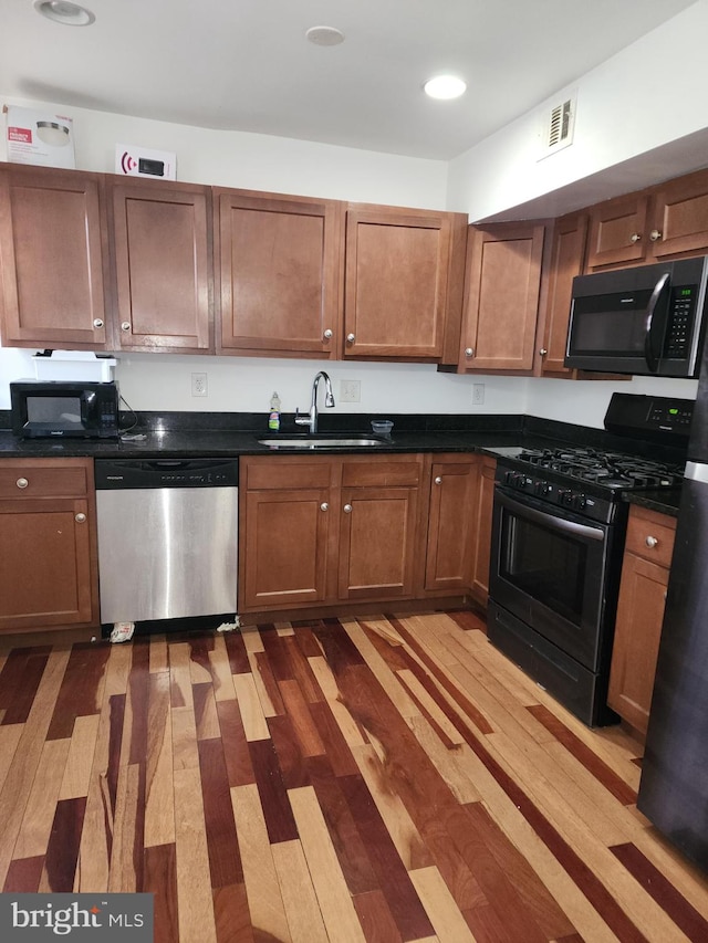 kitchen featuring black appliances, sink, and light hardwood / wood-style floors