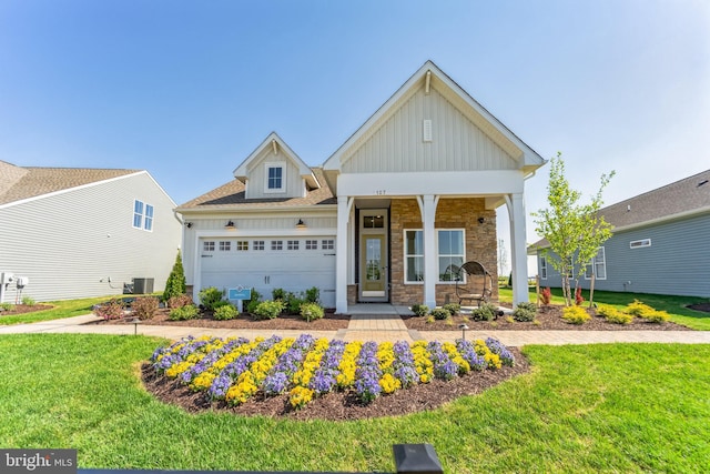 craftsman-style house featuring a front lawn, central AC, covered porch, and a garage