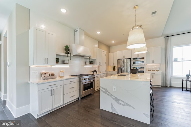 kitchen with stainless steel appliances, white cabinetry, an island with sink, and custom exhaust hood