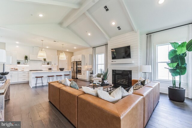 living room with high vaulted ceiling, a fireplace, dark wood-type flooring, and beamed ceiling