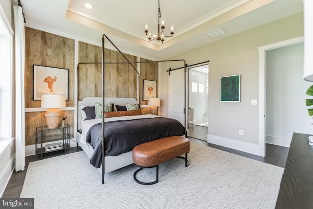 bedroom with dark hardwood / wood-style flooring, a notable chandelier, a barn door, and a raised ceiling