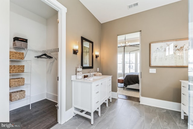 bathroom featuring a notable chandelier, tile floors, and vanity with extensive cabinet space