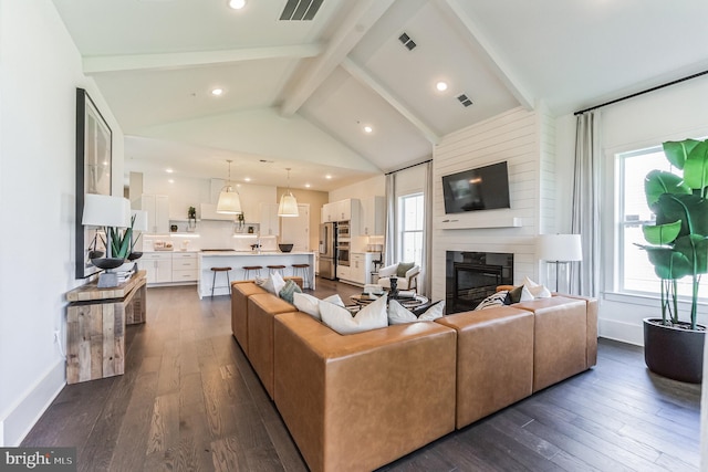 living room with high vaulted ceiling, a large fireplace, beam ceiling, and dark hardwood / wood-style flooring