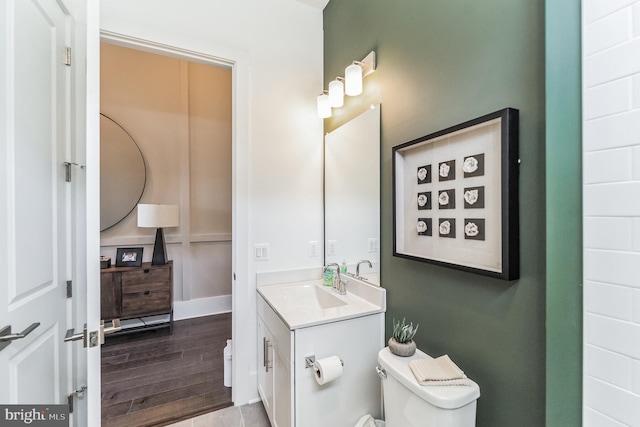 bathroom with hardwood / wood-style floors, vanity with extensive cabinet space, and toilet