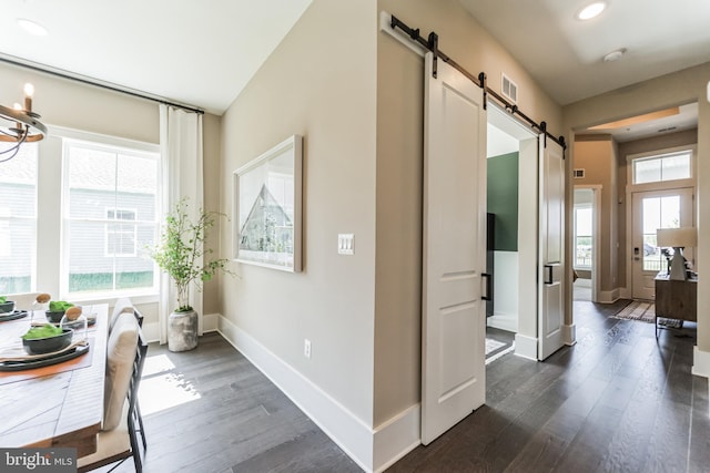 corridor with a barn door and dark wood-type flooring