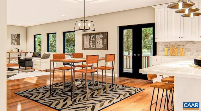 dining room with a notable chandelier, light hardwood / wood-style flooring, and french doors