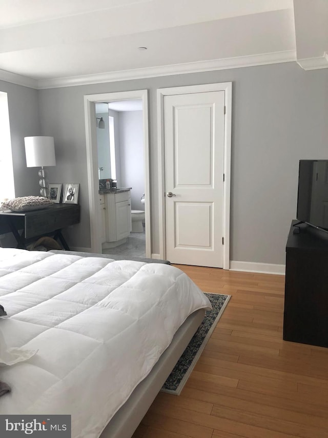 bedroom with ensuite bathroom, light hardwood / wood-style flooring, and crown molding