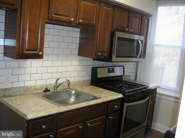 kitchen featuring sink, tasteful backsplash, stainless steel appliances, and light stone countertops