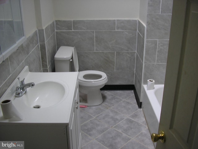 bathroom with vanity, tile floors, toilet, and tile walls