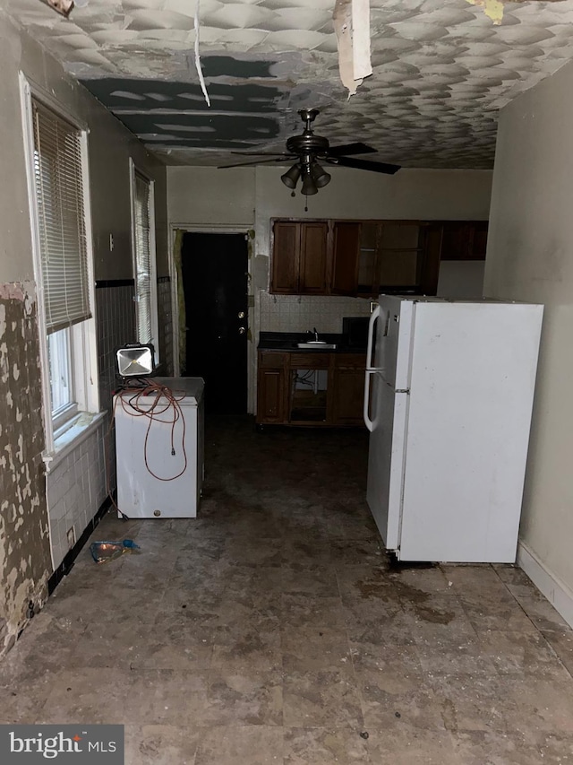 kitchen with ceiling fan, white fridge, washer / dryer, and sink