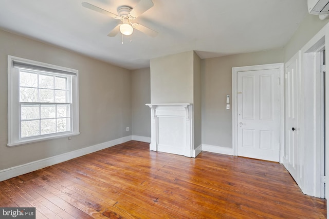 unfurnished room featuring a wall unit AC, ceiling fan, and dark hardwood / wood-style floors