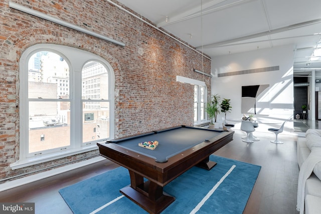 game room with brick wall, billiards, dark wood-type flooring, and a high ceiling