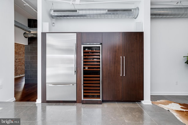 interior space with wine cooler, dark brown cabinetry, tile patterned floors, and built in refrigerator