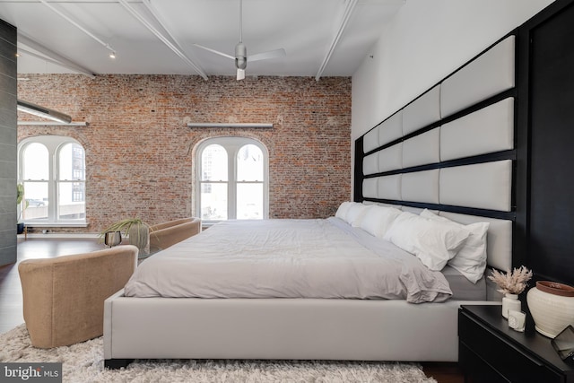 bedroom featuring brick wall, multiple windows, and light wood-type flooring