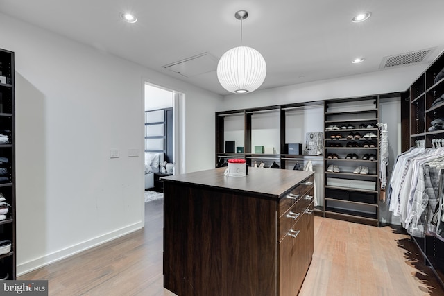 kitchen featuring dark brown cabinetry, a center island, hanging light fixtures, and light hardwood / wood-style floors