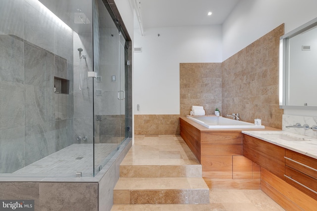 bathroom featuring tile walls, independent shower and bath, vanity, and tile patterned floors