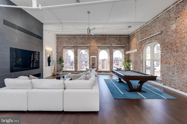 living room featuring dark wood-type flooring, a healthy amount of sunlight, a high ceiling, and pool table