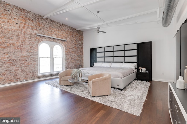 bedroom featuring beam ceiling, brick wall, and dark hardwood / wood-style floors