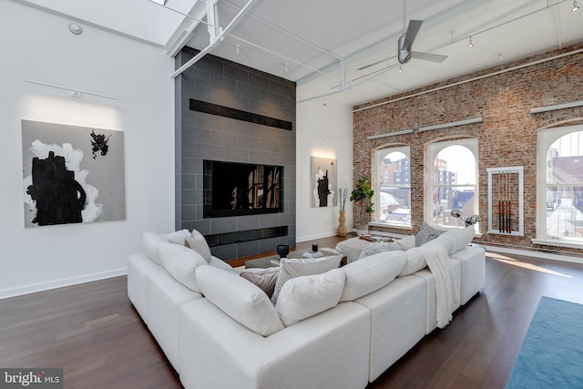 living room featuring ceiling fan, a high ceiling, and dark hardwood / wood-style floors