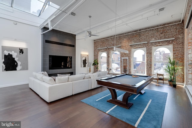 rec room featuring a skylight, pool table, a towering ceiling, and dark hardwood / wood-style flooring