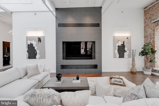 living room with hardwood / wood-style floors, a tiled fireplace, and a towering ceiling