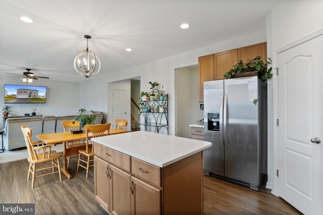 kitchen with a center island, ceiling fan with notable chandelier, dark hardwood / wood-style flooring, hanging light fixtures, and stainless steel fridge