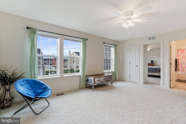 living area featuring light colored carpet and ceiling fan