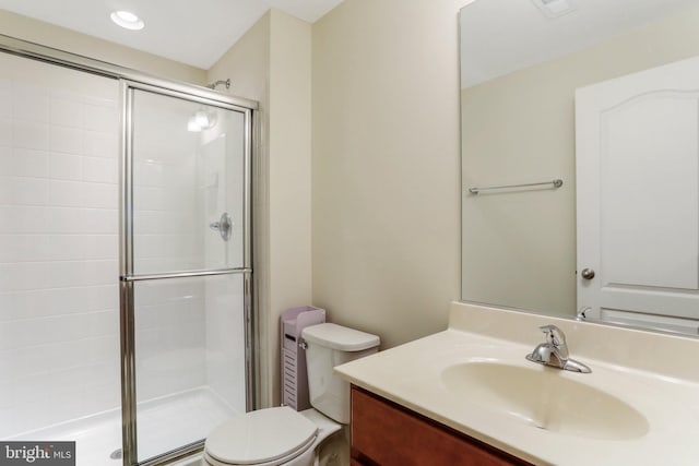 bathroom featuring a shower with shower door, toilet, and oversized vanity