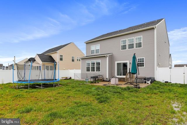 back of house featuring a trampoline, a patio area, and a lawn