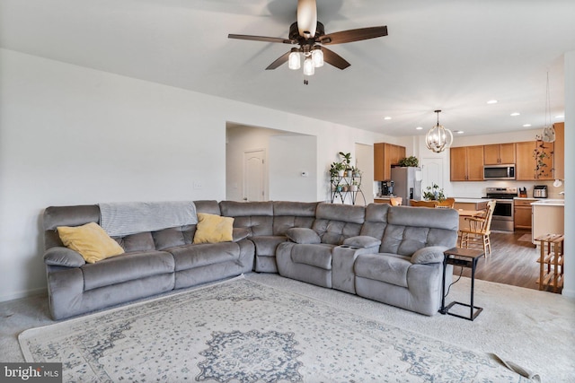 carpeted living room featuring ceiling fan with notable chandelier